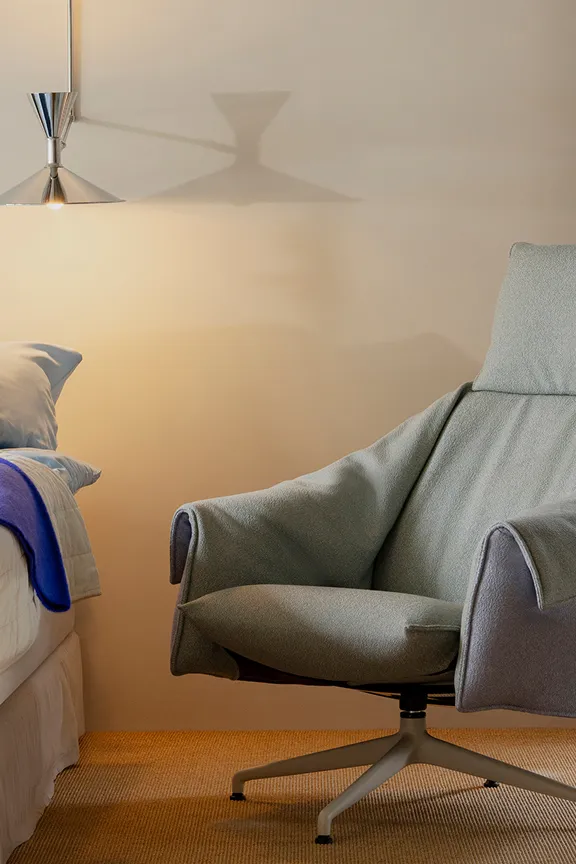 Der Loungechair Bascule von Vitra steht in einem gemütlichen Wohnzimmer neben einer Stehleuchte.